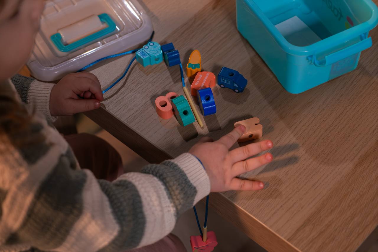 Kinder spielen gemeinsam mit dem Fädelspiel