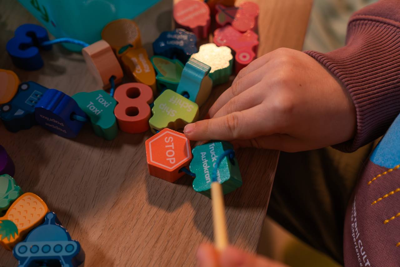 Hand beim Fädeln einer Perle