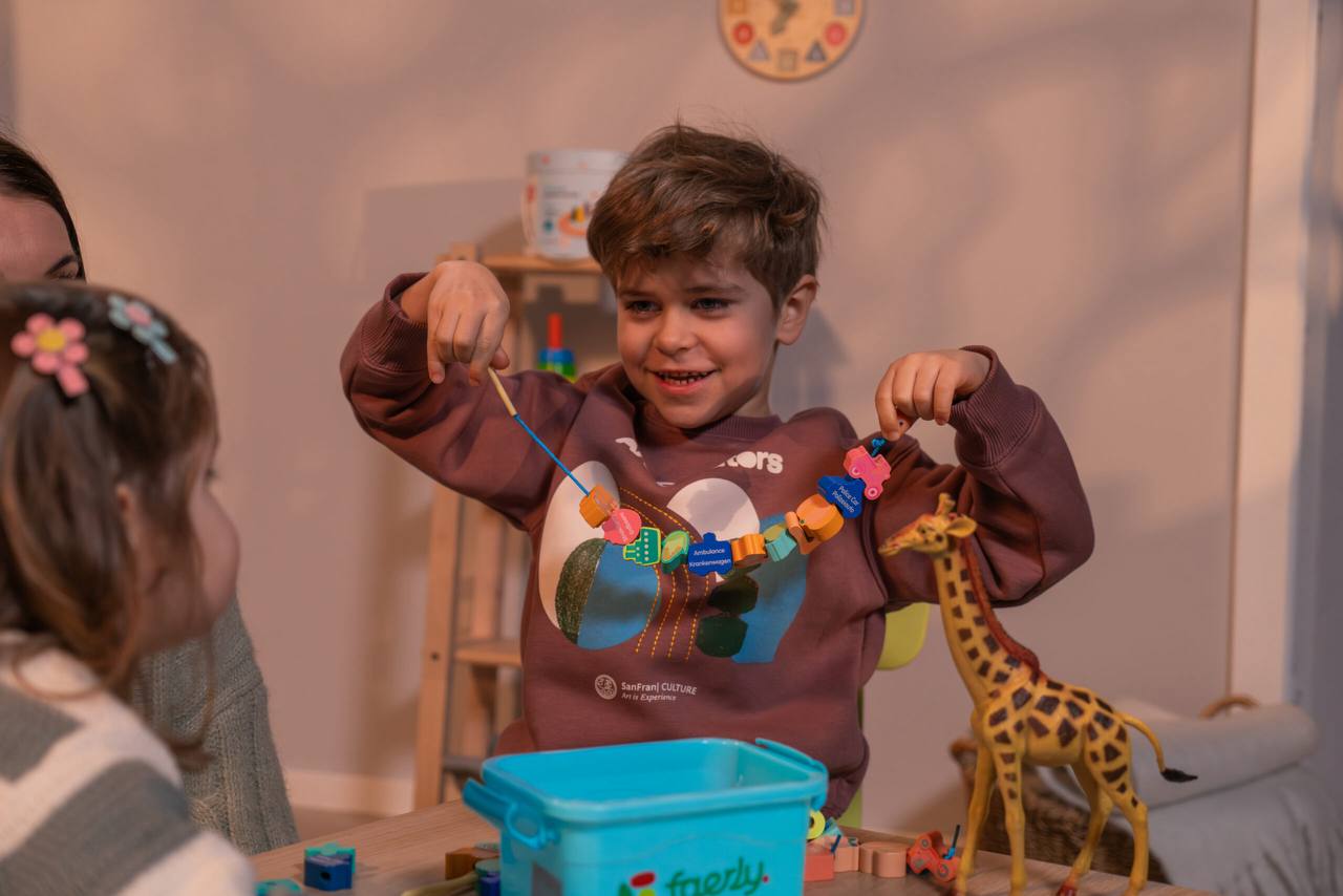Kind zeigt stolz sein gefädeltes Holzspielzeug
