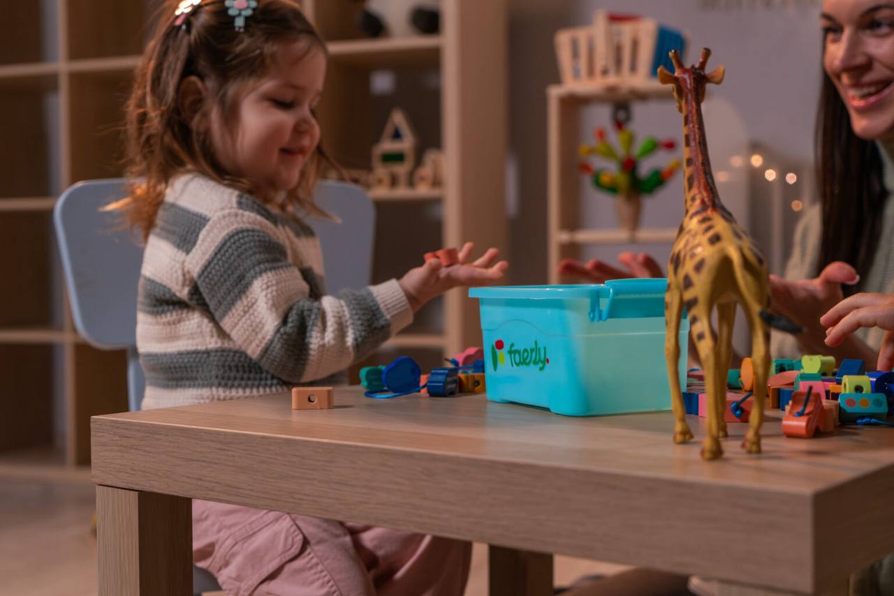 Glückliches Kind spielt mit Faerly Fädelspiel